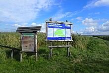 Zdjęcia tablic informacyjnych na tle łąk, szuwarów i nieba