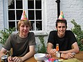 Two people wear party hats at a birthday party.