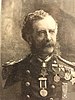 Head of a white man with wavy hair and a drooping mustache wearing a military jacket with shoulderboards.