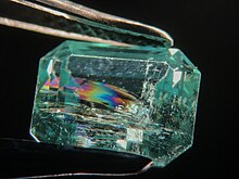 The foreign material inside this fracture-filled emerald appears rainbow-colored under darkfield illumination.