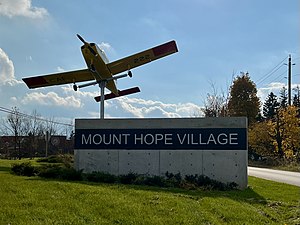 Sign of Mount Hope with a Beechcraft CT-134 Musketeer mounted next to it.[1]