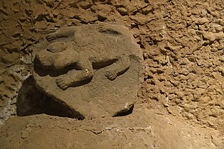 Carved stone with animal (possibly a reptile, felid, or wolverine) in high relief