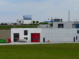 Blick über den Feuerwehrstützpunkt hinweg zur Besucherplattform auf dem Infopoint mit Baustellenschild (Juni 2013)