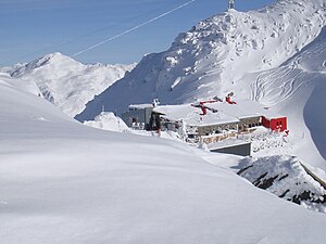 Glungezerhütte vom Grat zur Sonnenspitze, dahinter Seile und Stütze einer Seilbahn des Bundesheers, im Hintergrund der Malgrübler