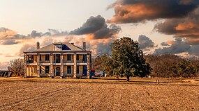 Photo d'une maison avec un champ et des arbres.