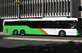 Light green, orange, and white bus stopping in front of multi-story building. (from Transport)