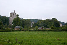 View of a stone tower and wooden buildings behind an open field