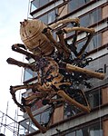 A large mechanical spider on the side of a tall building.