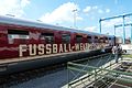 Un train rouge et or orné d'un pavillon allemand en quai.