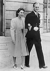 Photographie en noir et blanc d'un couple : la femme porte une robe claire, l'homme a un uniforme de couleur sombre.