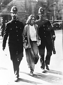 A woman under arrrest walking between two policemen