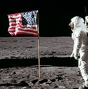 Cropped photo of Buzz Aldrin saluting the flag. The fingers of Aldrin's right hand can be seen behind his helmet.
