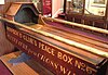 Adult-sized wooden cradle with "Henpeck'd Club's peace box" written on the side