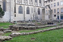 Ruines d'une église situées dans un jardin. En arrière-plan, la façade nord de la cathédrale actuelle.