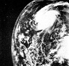 Black and white satellite image of a tropical cyclone, located near the center of the image. The cyclone has signs of rotation, but due to the low quality of the image, lacks definitive features. As a result of the image angle, the curvature of the Earth is visible to the left of the image.