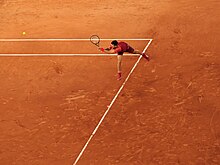 Photo de Novak Djokovic frappant un revers, sur fond de terre battue.