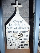 Boîte à crâne en forme de petite maison surmontée d'une croix avec une inscription dessus