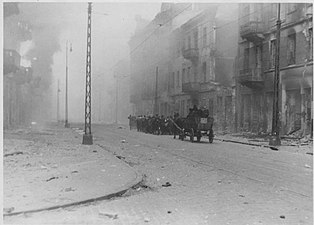 NARA copy #44, IPN copy #44 This is how the former Ghetto looks after having been destroyed Column heading North to Umschlagplatz on Zamenhofa Street, with burning Zamenhofa 25 / Wołyńska 2 on the left.