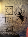 A spider and the letters "C C C" painted ona wall