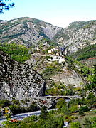 Pont de la D 316 vers La Vignasse et Saint-Léger. Village de Daluis en arrière-plan. En arrière-plan, les roches rouges du Dôme de Barrot.