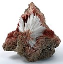 Natrolite sprays of stark white crystals are shooting out from a vug of inesite