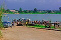 Bank of Oguta Lake showing human activities and rural dwellers. These include motorcyclists, loaded pontoon and automobile drivers engaged in movement of goods, services and people.