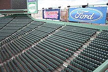 The Red Seat is seen completely surrounded by dark green seats in center field and right field in Fenway Park.