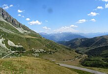 Photo shows a mountainous area with a winding road.