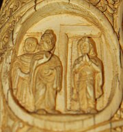 Ivory tusk with three figures: the Buddha, another attending monk, and a female figure standing in a doorway.