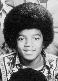 Black & white photo of Jackson as a chubby-cheeked teenager with afro hairstyle. He has a wide nose.