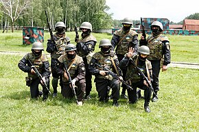 Eight armed, uniformed soldiers, four kneeling and four standing