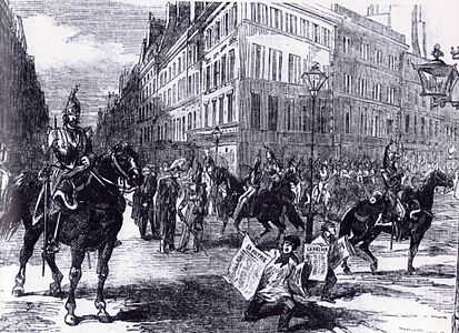 Cavaliers dans les rues de Paris le 2 décembre 1851. Leur officier confère avec des sergents de ville en bicorne tandis que deux crieurs de journaux vendent le quotidien bonapartiste La Patrie, l'un des imprimés exceptionnellement non interdits. Gravure publiée dans The Illustrated London News[136].