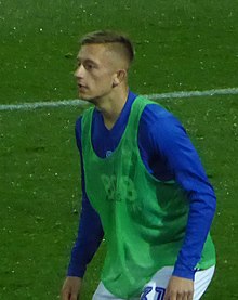 Lean young man with short fair hair wearing sports kit