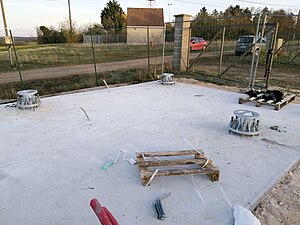 Plate-forme en béton avec les points d'ancrage du pylône.