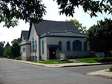 A white building with blue trim sits at the corner of an intersection.