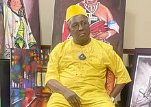 Photograph of Paul Joseph Mukungubila Mutombo, seated and dressed in yellow