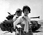 פליטים קוריאנים במהלך מלחמת קוריאה, מאחוריהם טנק פרשינג