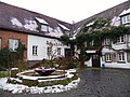 Eingang zur Brauerei mit dem Brunnen, der aus Teilen der ehemaligen Turbinenanlage besteht.