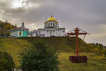 Поклонный крест на фоне монастыря