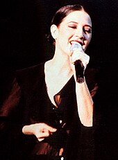 Sepiatone image of Donna De Lory singing with a microphone in her left hand.