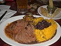 Authentic Cuban dish of ropa vieja (shredded flank steak in a tomato sauce base), black beans, yellow rice, plantains and fried yuca with beer