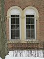 Front windows are trimmed in arched stone half-rounds and sills.