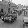 A British Army Universal Carrier leads some German prisoners-of-war into a Belgian town.