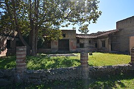 jardin entouré de batiments, en premier plan vestige de colonnades