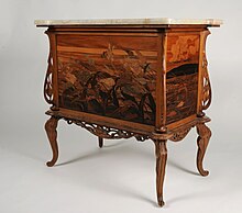 Cette petite commode à abattant possède deux tiroirs et repose sur des pieds galbés. Elle est ornée d'une marqueterie au décor floral sur la façade et les côtés, de motifs ajourés sculptés sur les montants et la ceinture et de motifs végétaux gravé sur le plateau en marbre.