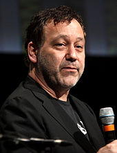 A man sitting next to a microphone placed on a table.