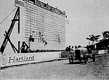 Photo d'un tableau d'affichage géant devant lequel passe une voiture.