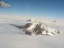 Massif montagneux isolé, cerné par un inlandsis, avec un versant abrité des vents dominants et dépourvu de neige.