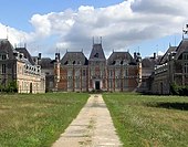 Grande bâtisse, de style Louis XIII, briques rouges, toit d'ardoise, trois étages, vue de loin, depuis le parc