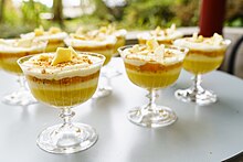 A several glasses containing yellow and white layered trifle